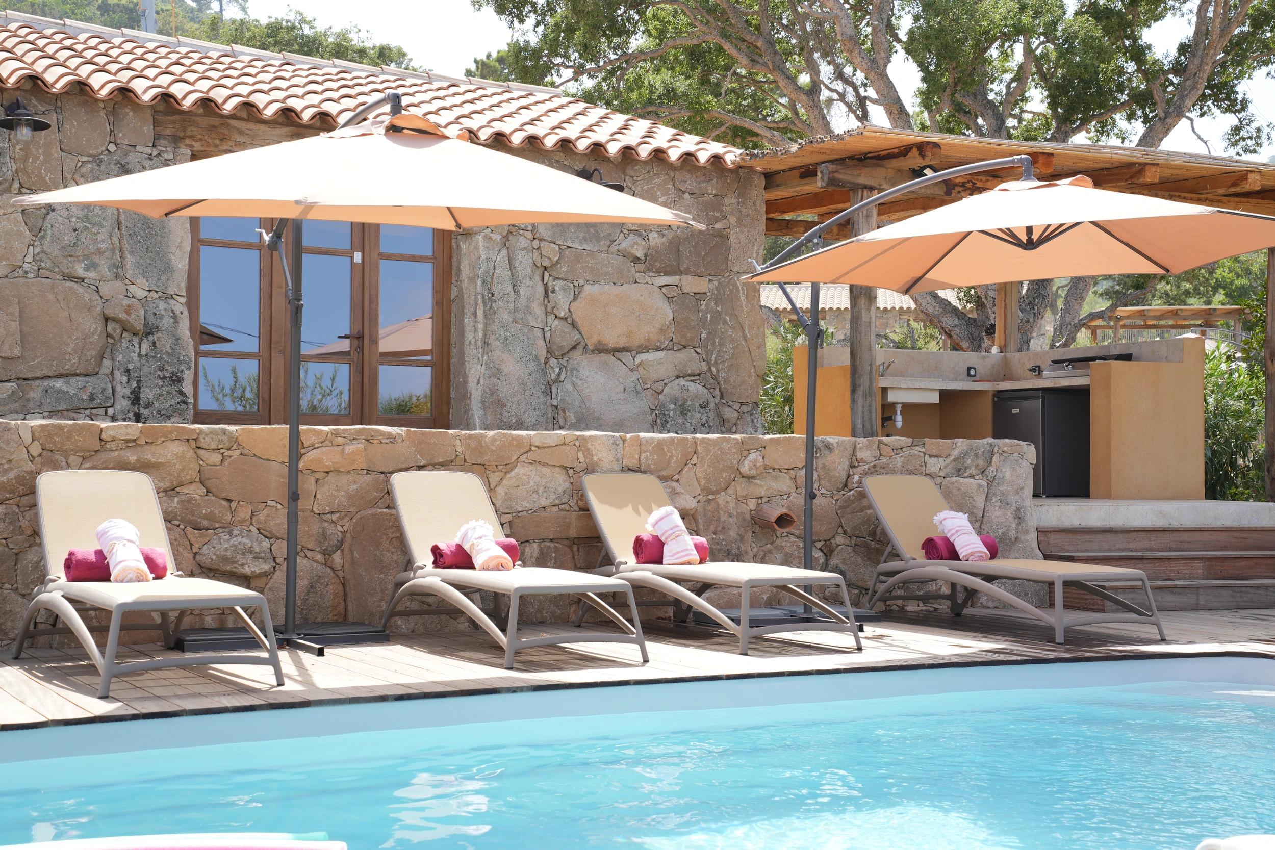 Piscine avec transats devant une maison en pierre de la Résidence Vista Blu entre Fautea et Tarco